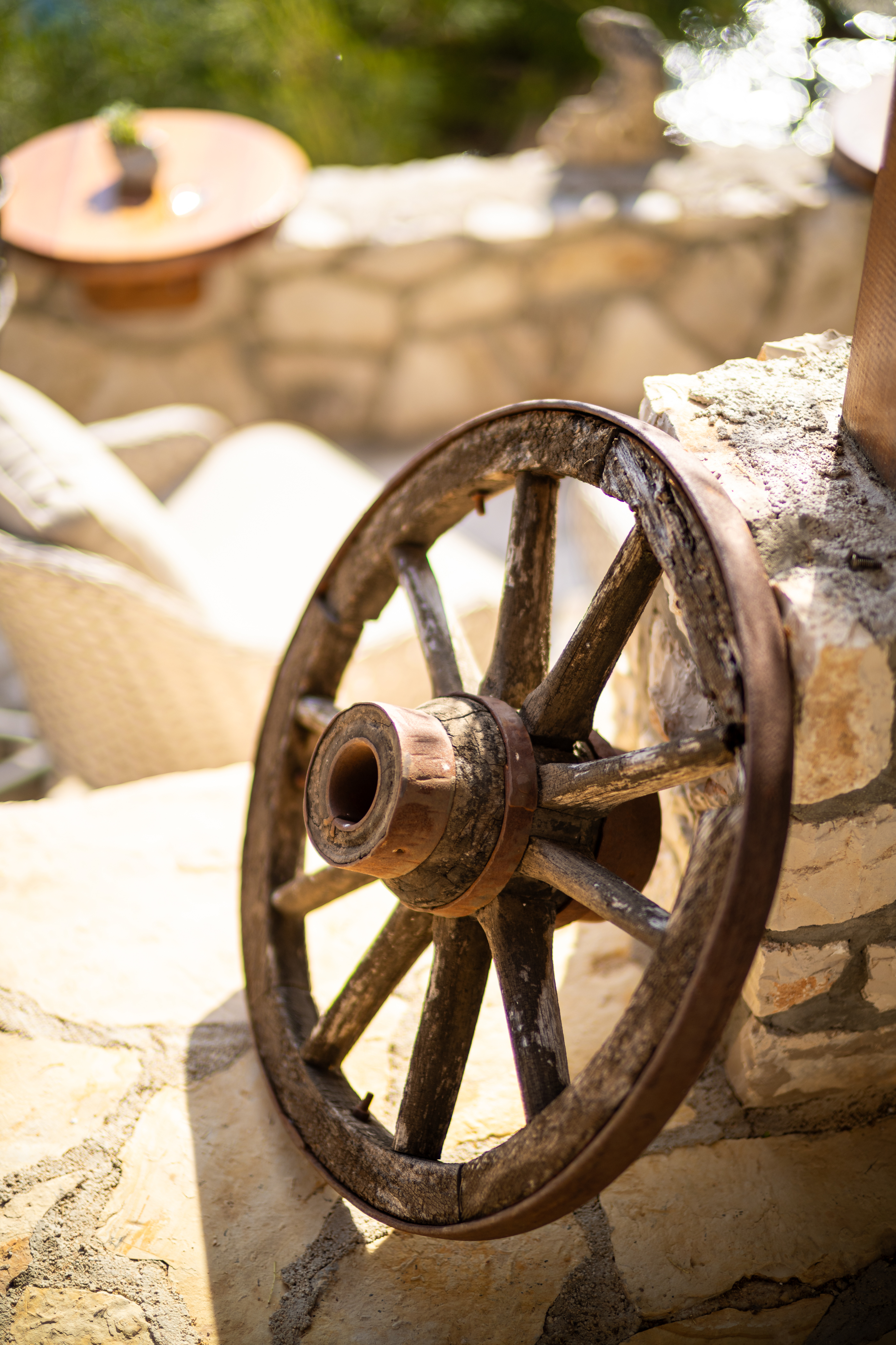 An old wheel leaning against a stone wall